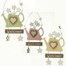 Závesná dekorácia v tvare krhličky s nápisom a kvetinami.