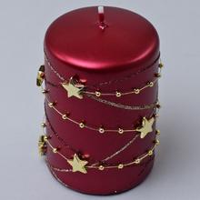 Vianočná sviečka v bordovej farbe s hviezdami a ozdobnými guľôčkami.