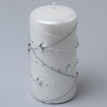 Biela vianočná sviečka s hviezdami a striebornou girlandou.