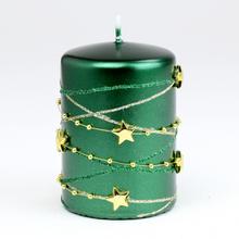 Zelená vianočná sviečka s hviezdami a ozdobami.
