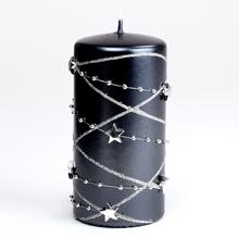 Čierna vianočná sviečka s hviezdami a striebornými ozdobami.