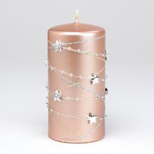 Ružovo zlatá sviečka s hviezdami a ozdobnými reťazami.