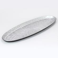 Strieborná oválna podložka s dekoratívnym vzorom.