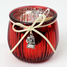 Červený svietnik z vrúbkoveného skla s ozdobou.