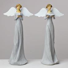 Dekoračný sivý anjel s bielymi krídlami.