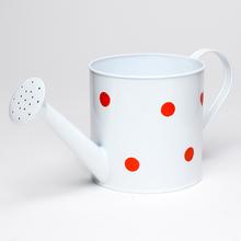 Biela kovová váza s veľkými červenými bodkami.