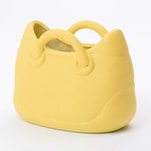Žltý keramický obal v tvare kabelky.