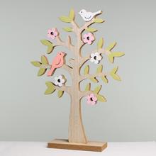 Drevený strom na podstavci s ružovými a bielymi kvetmi a vtákmi.