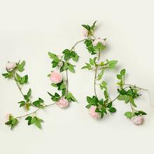 Umelá girlanda s ružovými kvetmi a zelenými listami.