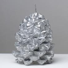 Strieborná sviečka v tvare šišky.