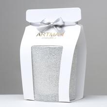 Biela vianočná sviečka v sklenenom obale s glitrom.