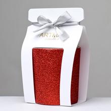 Červená vianočná sviečka v sklenenom obale s glitrom.