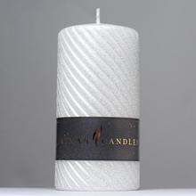 Biela vianočná sviečka s glitrom a prúžkovaným dizajnom.