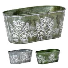 Kovový oválny obal s kvetinovým vzorom.