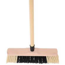 Metla s hustými štetinami a násadou.