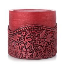 Červená okrúhla sviečka s dekoratívnym vzorom.