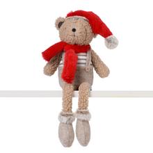 Béžový medveď sediaci s červenou čiapkou a šálom.