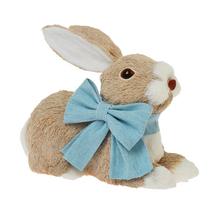 Slamený zajac ležiaci s modrou mašľou.