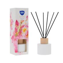 Difuzor s lotosovým kvetom v bielej fľaši a čiernymi tyčinkami.