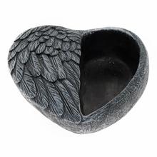 Cementový kvetináč v tvare srdca so zobrazenými krídlami.