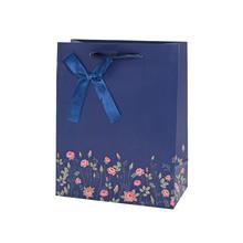 Darčeková taška s kvetinovým vzorom a modrou stuhou.