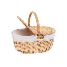 Ovalný piknikový košík svetlohnedej farby s bielou látkou a rúčkou.