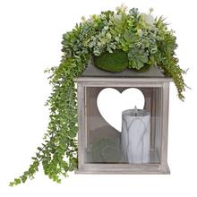 Smútočná väzba s dekoratívnymi rastlinami a sviečkou.