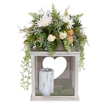 Smútočná väzba s kvetinami v drevenej lucerne srdcového tvaru.