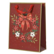 Vianočná papierová taška s červeným pozadím a kvetinovým vzorom.