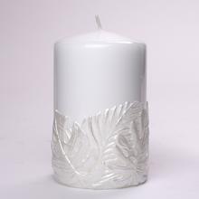 Biela sviečka s dizajnom listov monstera.