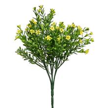 Umelý kvet s malými žltými kvetmi a zelenými listami.