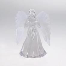 Sviečka v tvare anjela s bielymi krídlami.