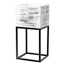 Biely obal na kvety s čiernym podstavcom.