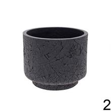 Čierny a biely keramický obal na kvetináč s prasklinami.
