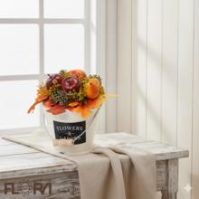 Jesenné aranžmá v bielej nádobe s ovocím a listami.