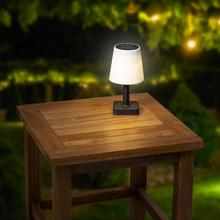 Solárna lampa s bielym tienidlo a čiernym podstavcom.