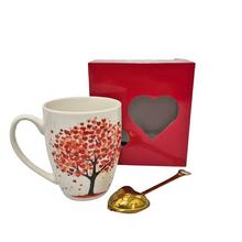Šálka s čajítkom s motívom stromu a červenou krabičkou.