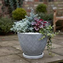 Biely keramický kvetináč s okrúhlou miskou a vzorom listov.