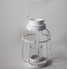 Biely kovový svietnik s lucernou a skleneným vnútrom.