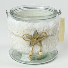 Biely svietnik s kožušinovým obalom a skleneným základom.