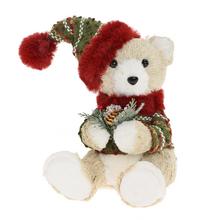 Sediaci medveď s krémovou farbou, čiapkou a sveterom, držiaci šišku.