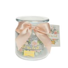 Sivá celoročná sviečka v skle s ozdobnou stuhou.